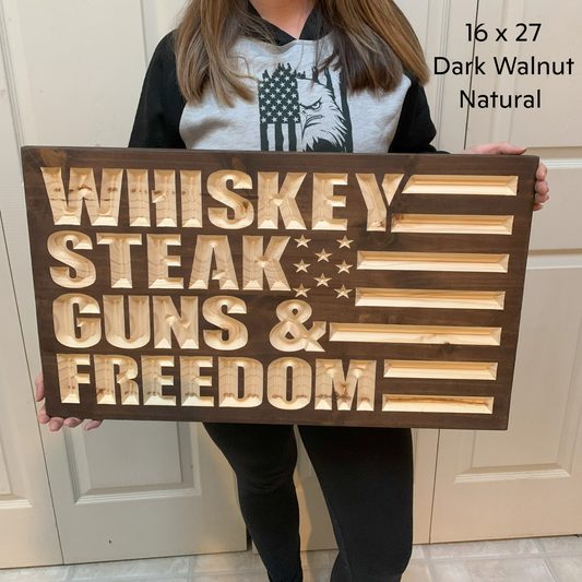 a woman holding a sign that says whiskey, steak, guns and freedom